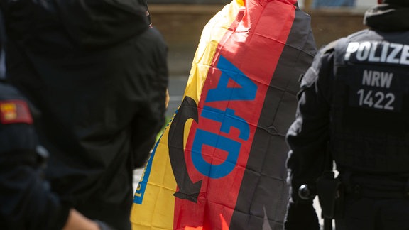 Ein Demonstrant mit einer AfD-Fahne ist zu sehen.